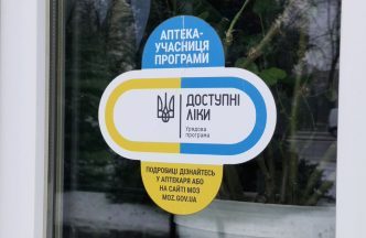 Наліпка «Доступні ліки» на дверях аптеки, що бере участь у державній програмі. Вона передбачає отримання необхідних препаратів безплатно або з великою знижкою.